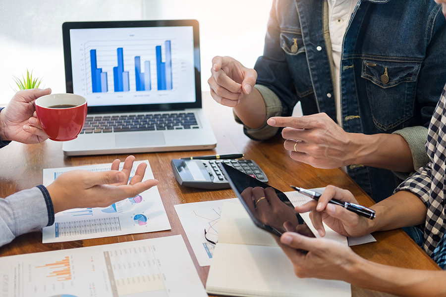 Personer sitter runt datorskärm med grafer