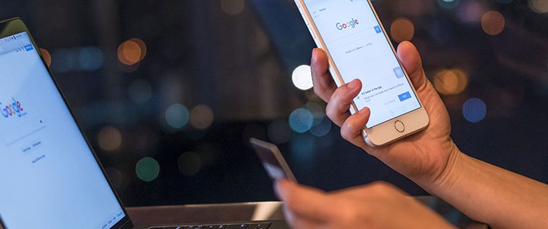Laptop och mobiltelefon som visar Googles startsida