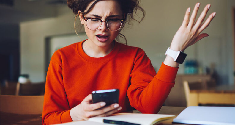 Besviken och irriterad kvinna med mobiltelefon