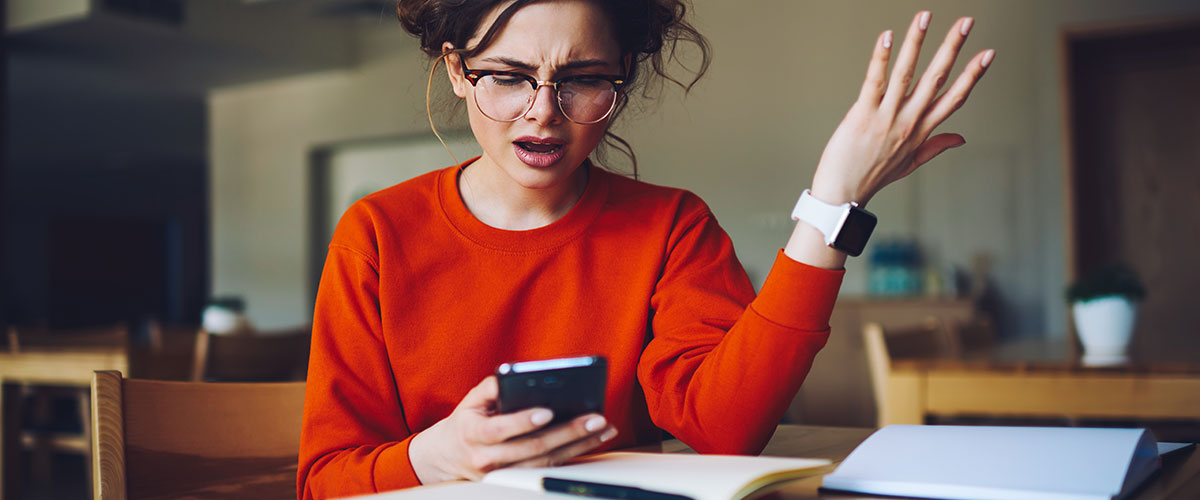 Besviken och irriterad kvinna med mobiltelefon